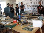 a group of people standing around a desk of tools.